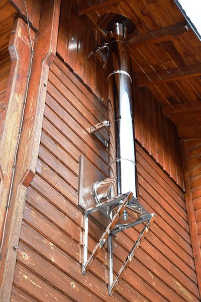 conduit de cheminée en acier inoxydable sur une ancienne grange avec traversée de toit
